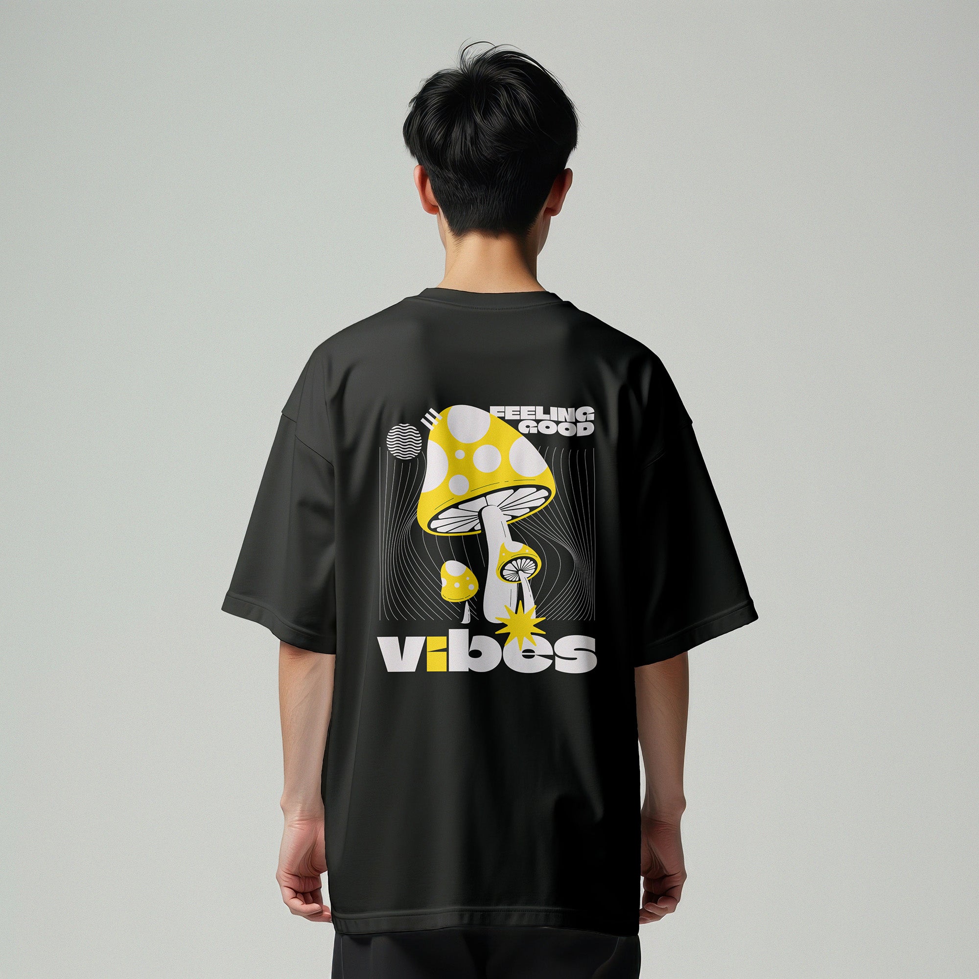 Person wearing a black t-shirt with a mushroom graphic and text on the back against a gray background