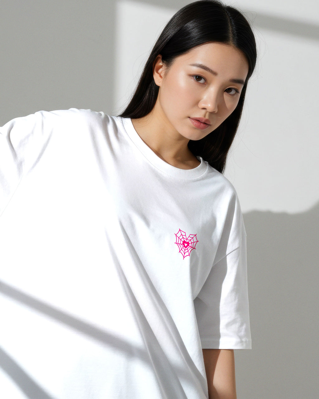 Woman wearing a white t-shirt with a pink flower design against a gray background