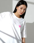 Woman wearing a white t-shirt with a pink flower design against a gray background